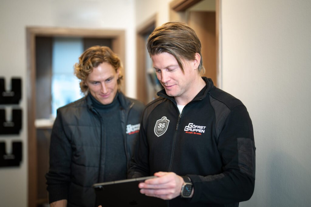 Two men looking at a technical device looking happy.