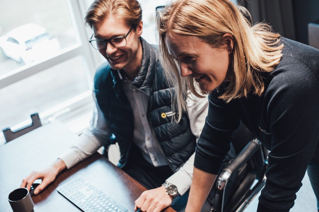 Two people collaborating while looking at a laptop.