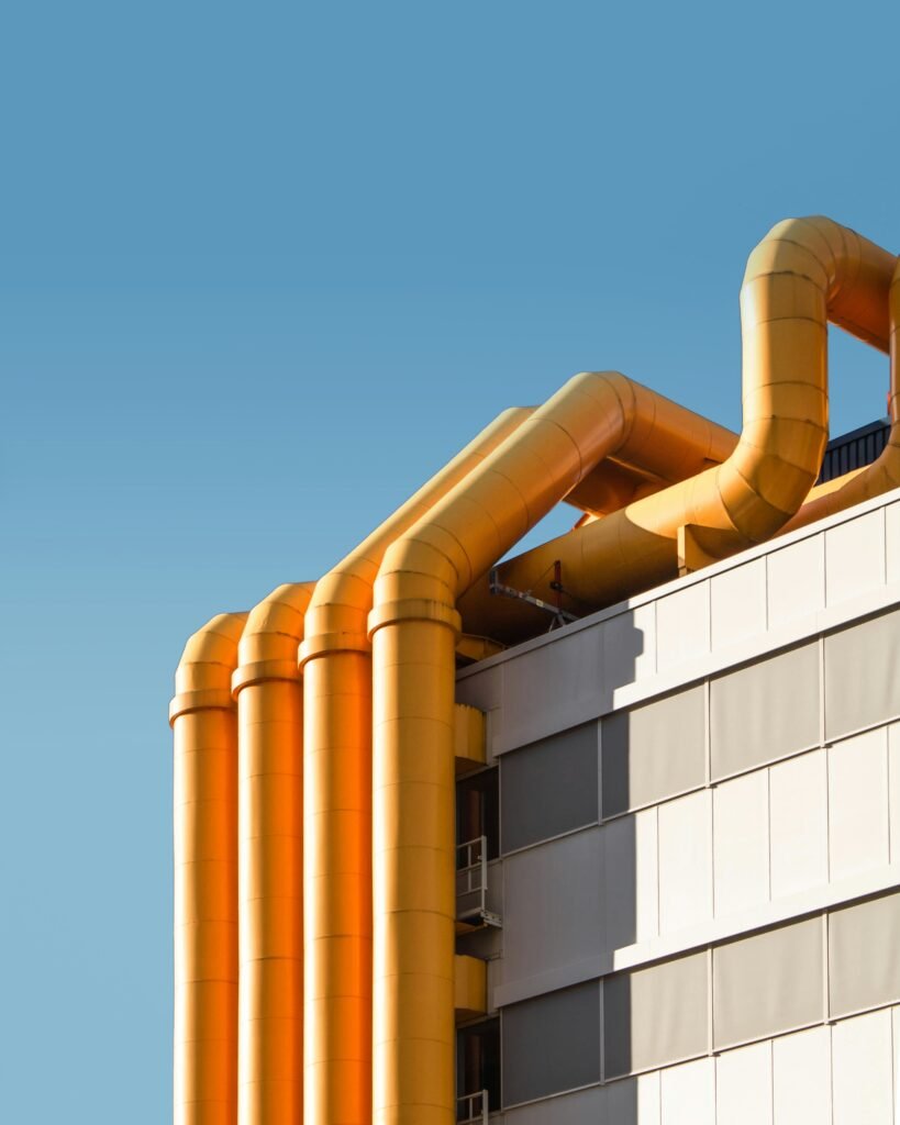 Yellow industrial pipes on a building wall.