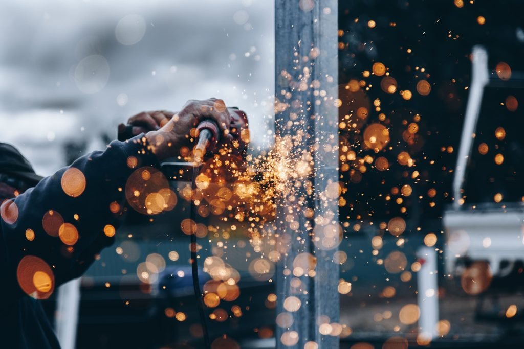 Worker cutting metal with sparks flying.